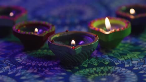 Lit-candles-in-decorative-clay-pots-on-patterned-table-top,-blown-out,-focus-on-foreground