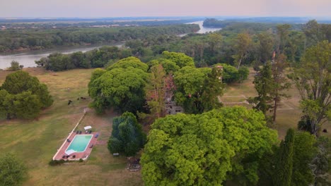 Drone-shot-flying-around-the-estancia-Santa-Cándida-in-Entre-Ríos,-Argentina-with-the-city-of-Concepción-del-Uruguay-appearing-in-the-background