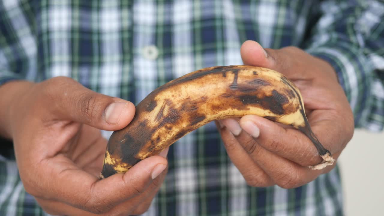 una persona que sostiene un plátano maduro