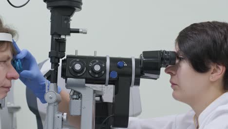 woman doctor is viewing through ophthalmoscope in eyes of patient in ophthalmologic clinic. professional inspection of vision