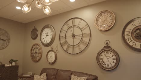 a beige living room wall full of roman numeral clocks set at different times