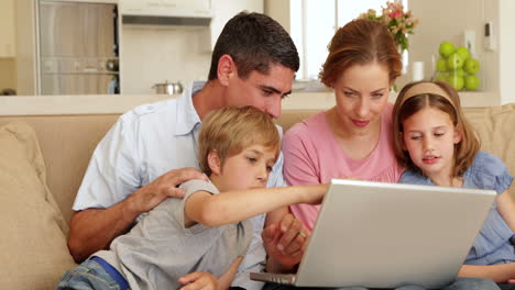 Glückliche-Familie-Sitzt-Auf-Dem-Sofa-Und-Benutzt-Gemeinsam-Einen-Laptop