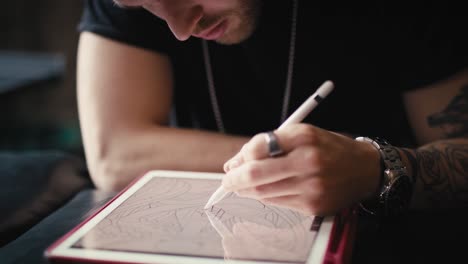 close up of  caucasian tattoo artist  designing motifs on digital tablet.