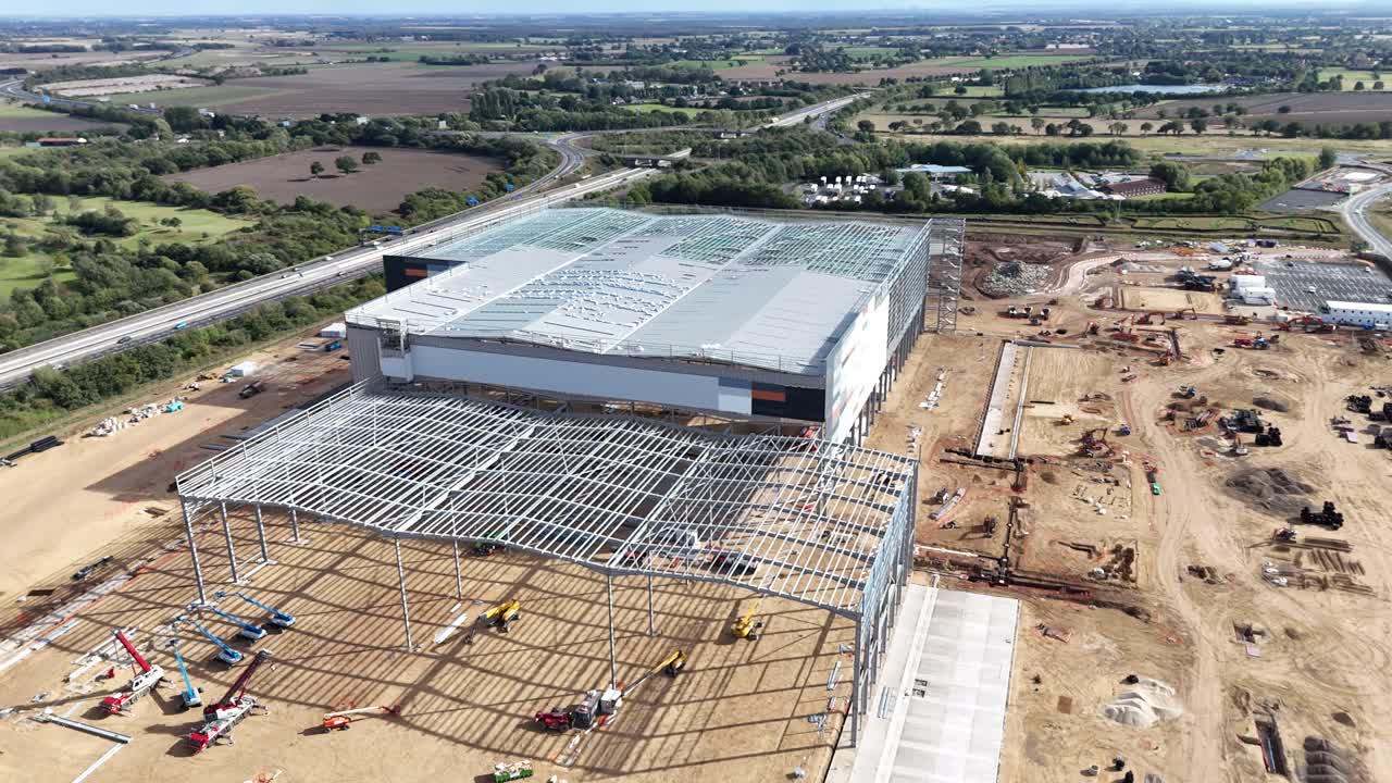 Vista aerea con drone di un grande cantiere industriale vicino a Brackley nel Northamptonshire, Inghilterra, che mostra strutture in acciaio, magazzini, scavi e la campagna circostante