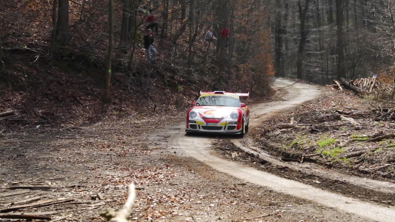 The Valasska Rally and the Porsche race car coming out of a bend into a short section between tree trunks will pass part of the circuit in the middle of the forest road captured in 120fps slow motion.