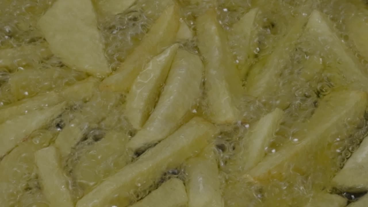 熱く油がはねる中で揚げられるフライドポテトのクローズアップ