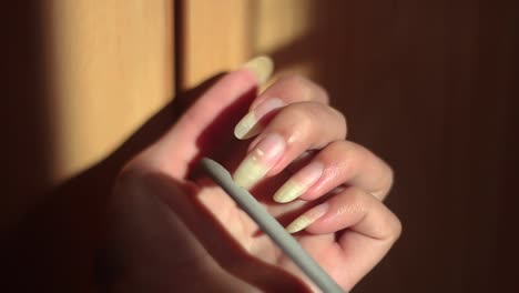 long natural nails being filed by a woman on the golden hour