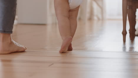 baby learning to walk toddler taking first steps with mother helping infant teaching child at home