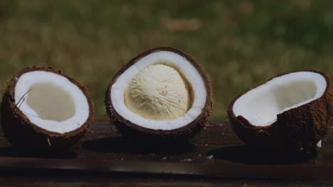 zoom out from three halves of coconut on wooden table, one in midst of germination process