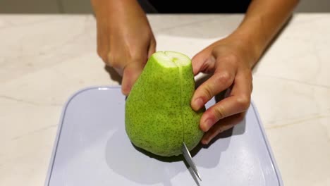 persona cortando una pera en una tabla de cortar