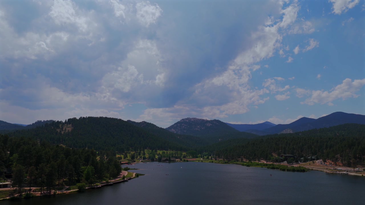 Luftfoto fra drone af Evergreen Lake i Evergreen, Colorado, med forbjerge, Denver Golfbane, Upper Bear Creek og Mt. Blue himmel. Front Range Rocky Mountains i sommer- og forårsvejr, solrig eller overskyet morgen, paddleboarding, panorering mod venstre.