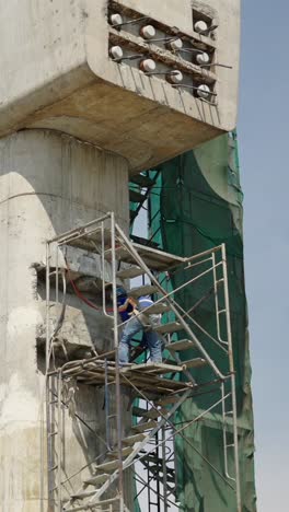 construction worker on scaffolding near a concrete pillar