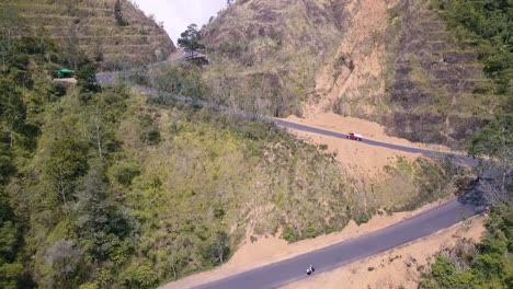 coche rojo conduciendo por una carretera con curvas que conduce a un paso de montaña