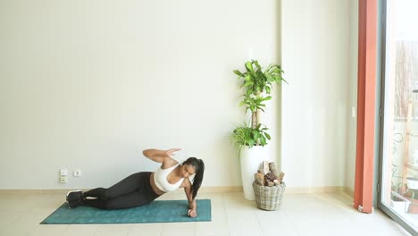 Ethnic-sportswoman-performing-Side-Forearm-Plank-pose-on-mat