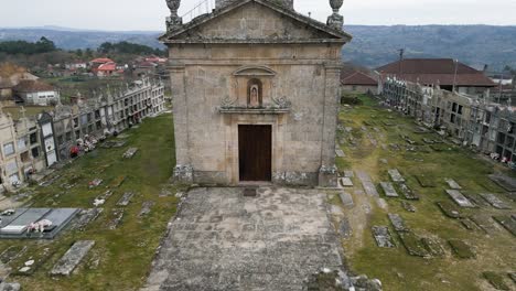 fast aerial pullback from carved figurine in apse of old mossy church building surrounded by cemetery of santa maria de freas in punxin ourense galicia spain