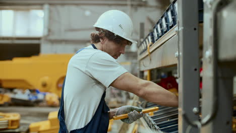 operaio maschio che dispone i componenti sugli scaffali in una fabbrica industriale