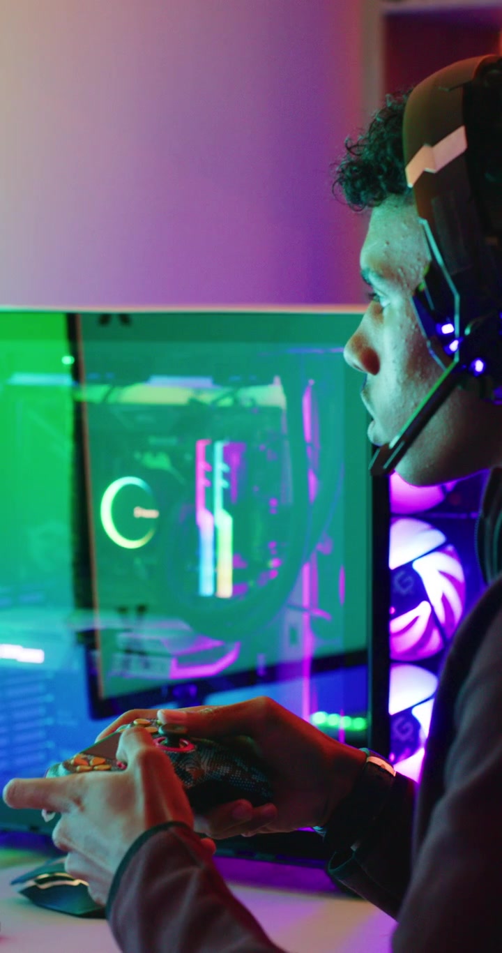 Giovane gamer che gioca a un videogioco su PC in una stanza illuminata al neon