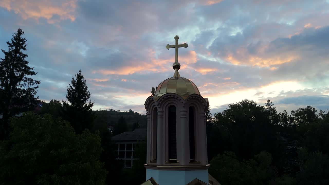 Aerial drone close-up of the Orthodox Church in Jajce, Bosnia and Herzegovina at sunset historic stone architecture surrounded by green hills and medieval town views