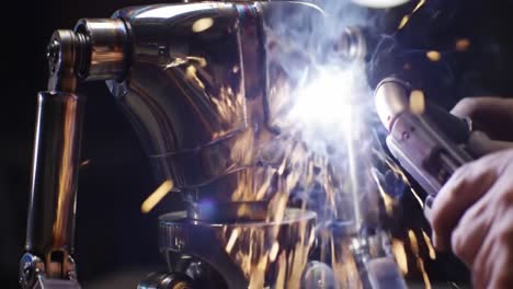 a skilled technician works on assembling a metallic robot in a workshop filled with tools and equipment. the ambient light highlights the craftsmanship involved in the process.