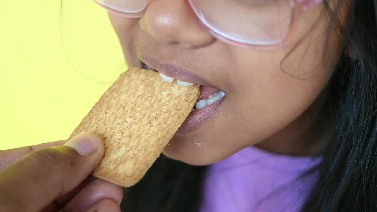 una chica comiendo una galleta.