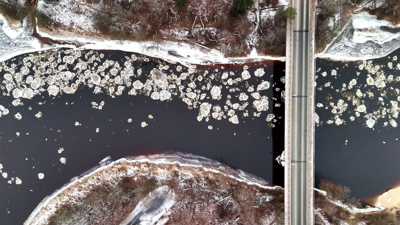 Top view over a bridge under which ice floes float past on the river