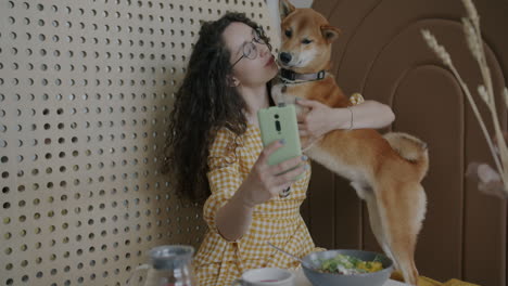 woman taking a selfie with her shiba inu dog in a cafe