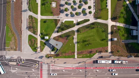 top down aerial - main street in the center of gdynia by the central park - cars and public transport moving through the streets - modern park and urban space in the city center