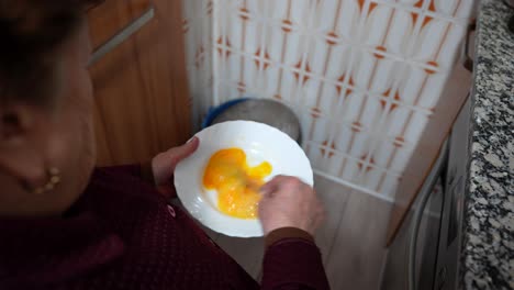 granny beating eggs in a plate to cook an omelette in old kitchen