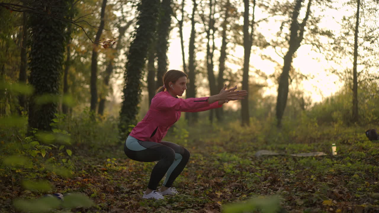 Donna che fa squat durante un allenamento all'aperto in un bosco