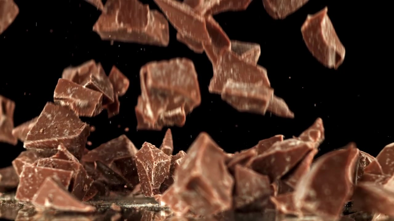 Pezzi di cioccolato che cadono al rallentatore su sfondo nero
