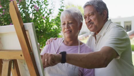 video de una feliz pareja de ancianos biraciales pintando en el jardín