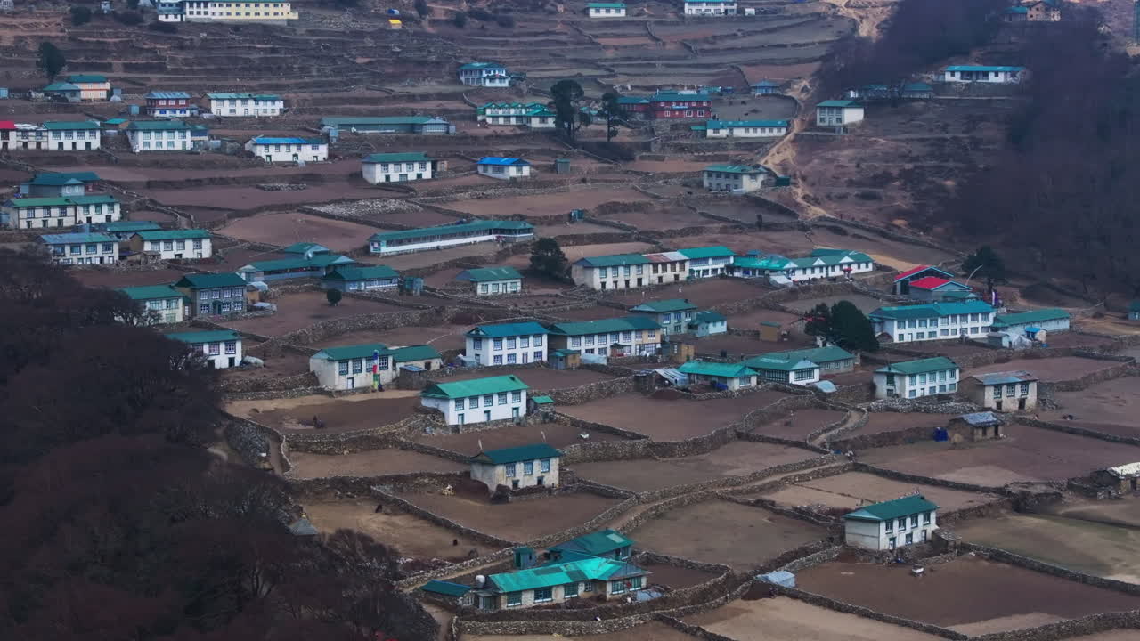 Drone view of Phortse Village along Everest base camp trek, showing rural Himalayan lifestyle, farmlands, distant peaks, and scenic terrain lands