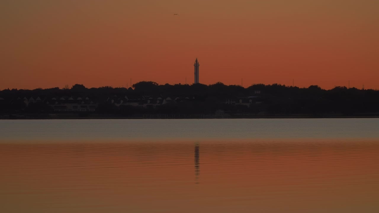 Silhouette dell'iconica Citrus Tower di Clermont contro un cielo arancione brillante al tramonto sopra il Lago Minneola nella Florida Centrale.