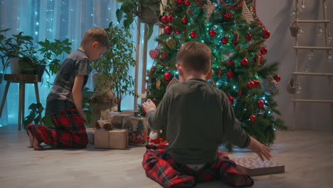 two children running towards their presents on christmas morning. two boys in pajamas running to look at the gifts under the christmas tree. high quality 4k footage