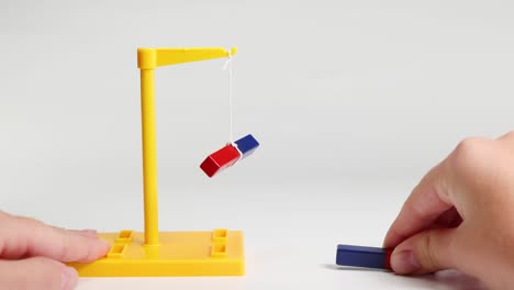 hands manipulate magnets to explore attraction and repulsion, using a suspended setup with clear lighting and simple composition