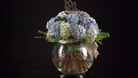 carnation floral arrangement chrysanthemum with ribbon in water tank spinning in black background