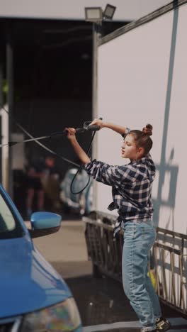 woman washing a blue car at a commercial car wash