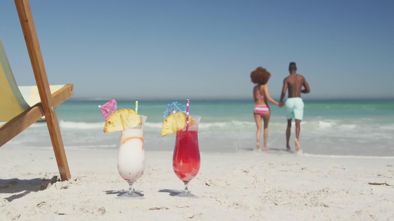 African american couple ready to swim with cocktail in foreground