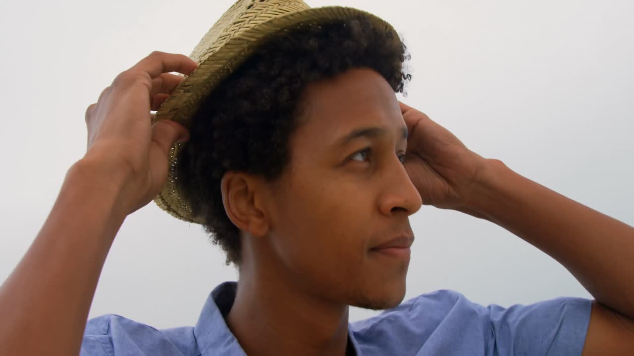 vista frontal de un hombre afroamericano con sombrero en la playa 4k