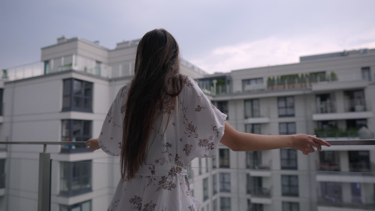 발코니 에 있는 여자 가 도시 풍경 을 상 하고 있다