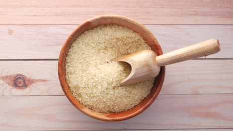 wooden bowl of uncooked rice with scoop