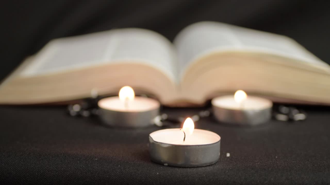 Tre candele tealight con libro aperto sullo sfondo, inquadratura media