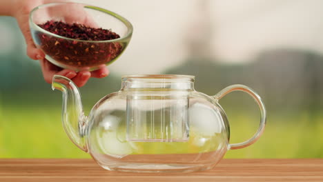 adding loose leaf tea to a glass teapot