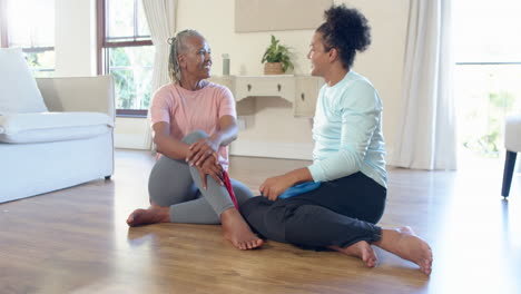 senior woman and caregiver exercising with resistance bands at home, sharing smile
