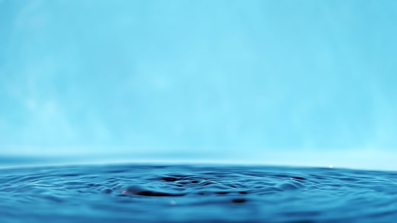 파란색 배경에 떨어지는 물방울과 함께 물 표면의 느린 모션 4k 비디오.