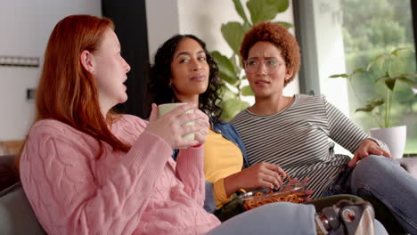 watching tv, diverse female friends hanging out on couch with snacks and drinks