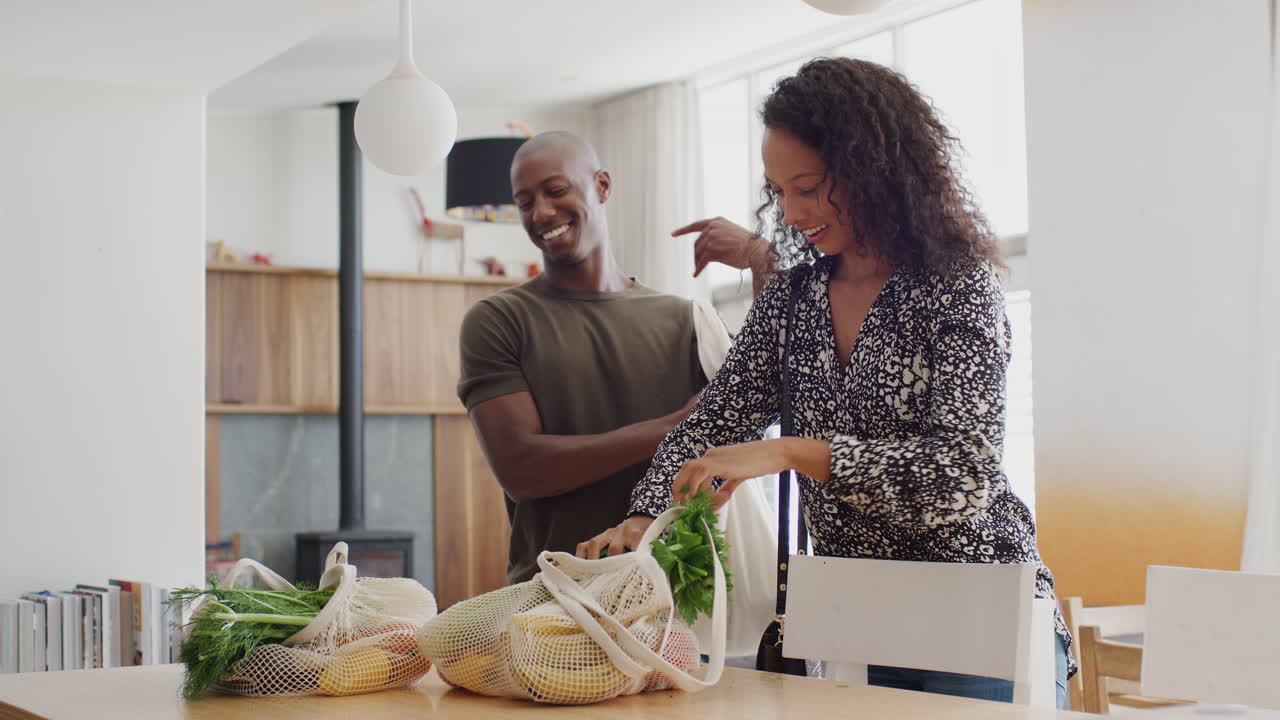 Couple Returning Home From Shopping Trip Unpacking Plastic Free Grocery Bags