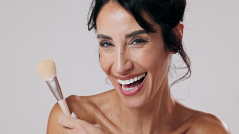 mujer sonriente sosteniendo un pincel de maquillaje