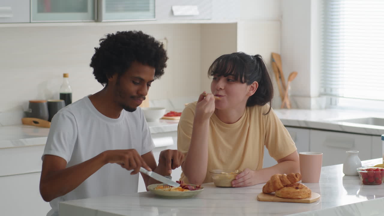 Bi-ethnic Married Couple Having Breakfast at Home Kitchen