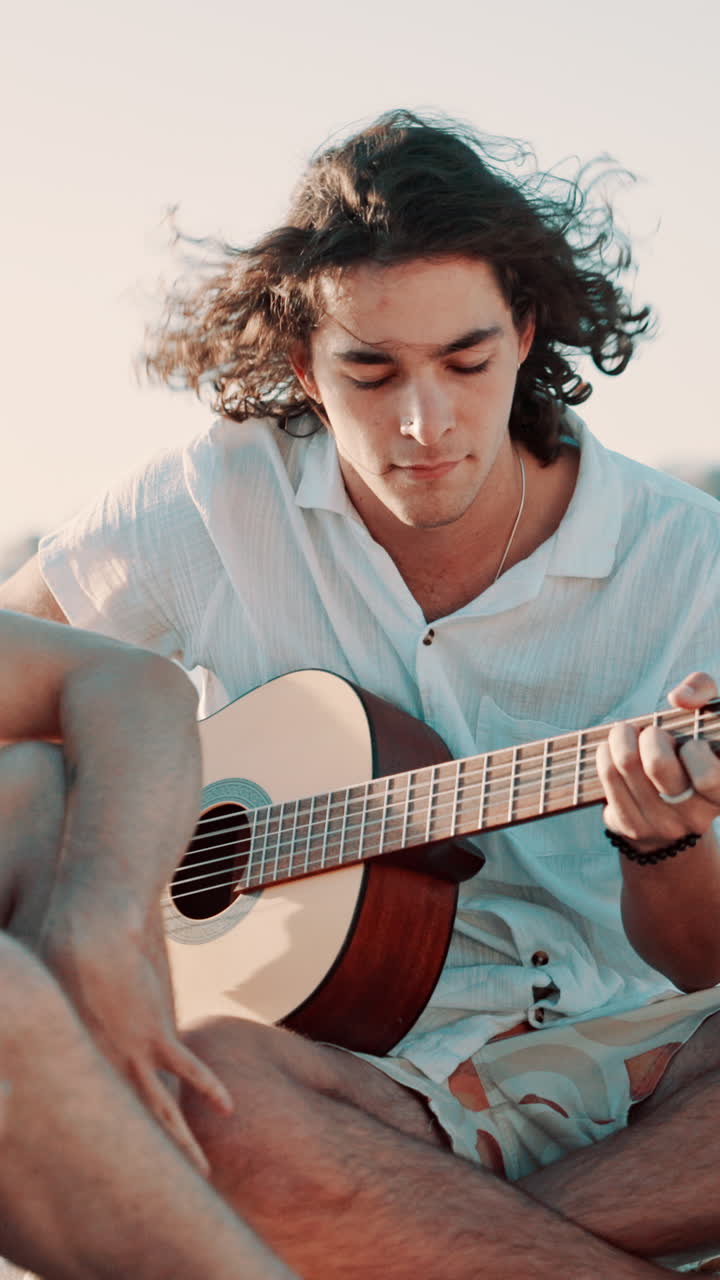 Giovane uomo che suona la chitarra acustica sulla spiaggia
